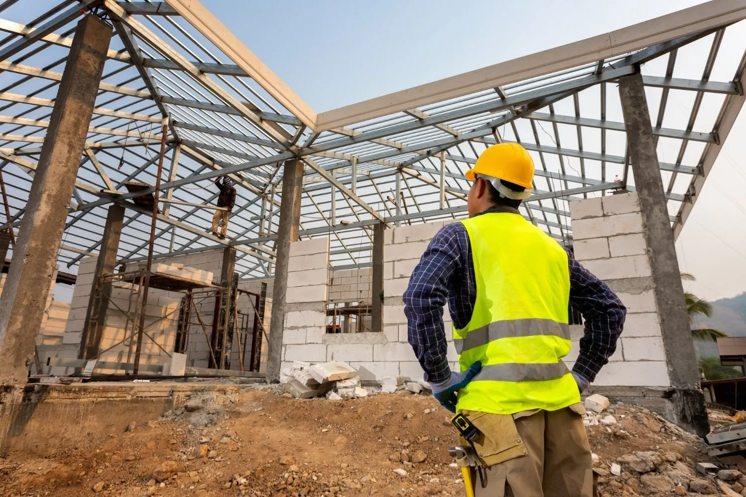 Site supervisor in a hard hat inspecting new block walls and roof framing