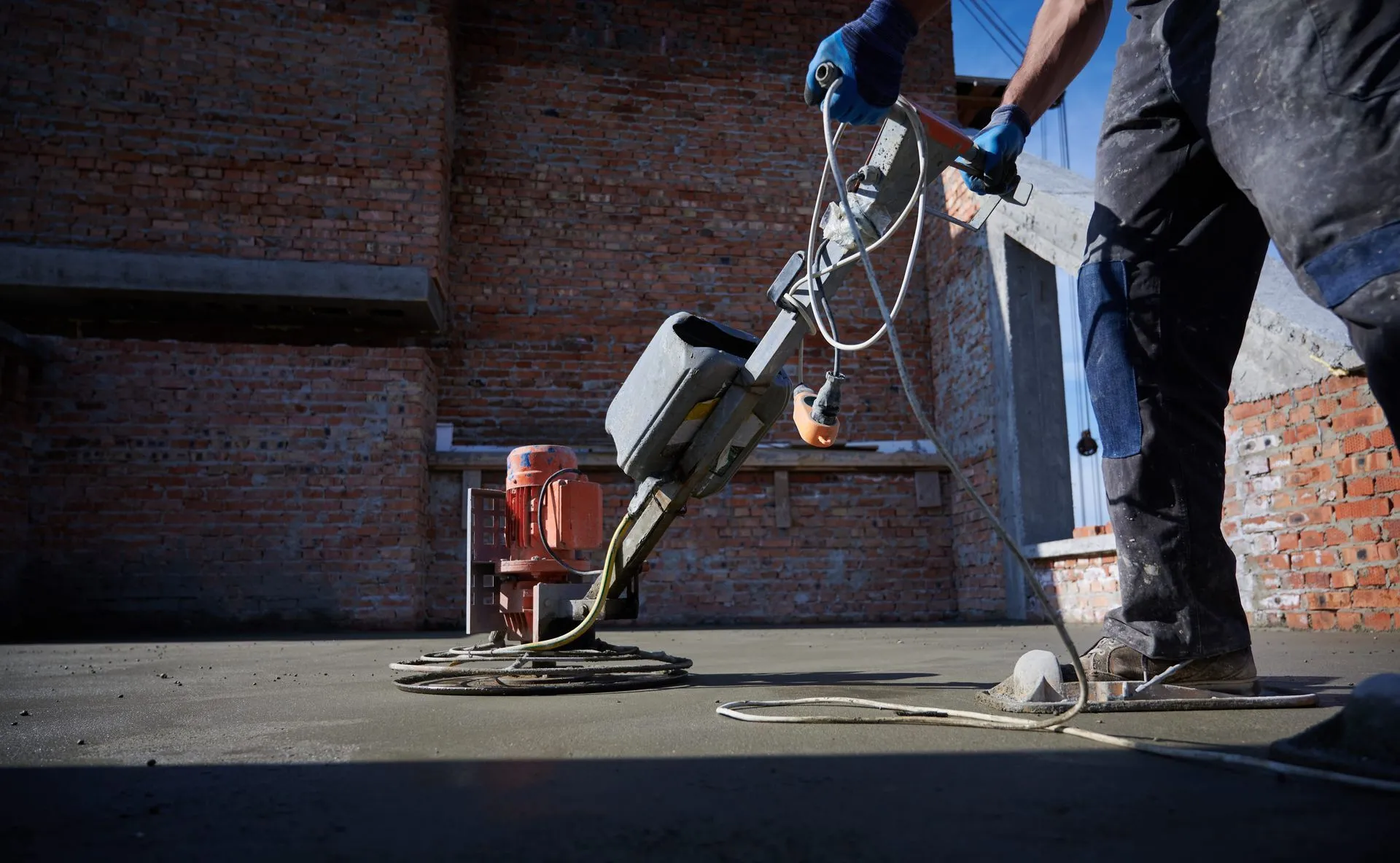 Worker running a power trowel to finish a concrete floor