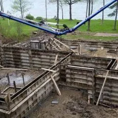 Concrete pump boom filling foundation wall forms on a lakeside lot