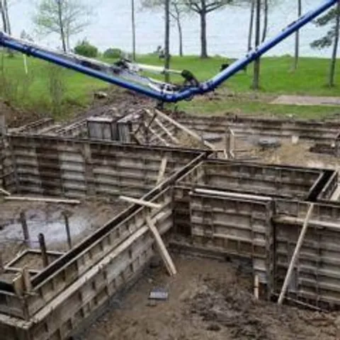 Concrete pump boom filling foundation wall forms on a lakeside lot